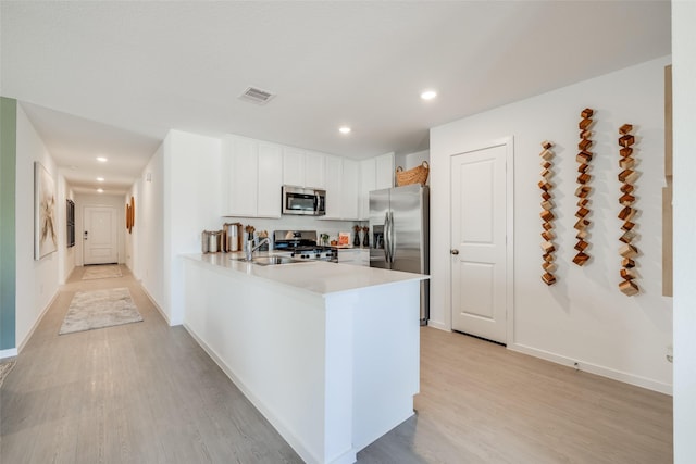 3012 Wild Dunes Dr, Katy, TX 77493 - kitchen featuring stainless steel appliances, a sink, light countertops, light wood-type flooring, and a peninsula