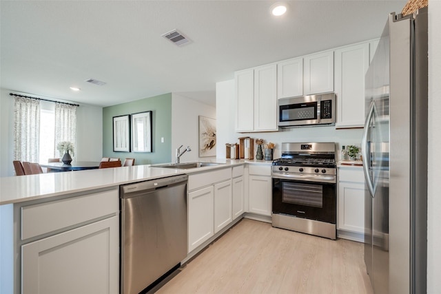 3012 Wild Dunes Dr, Katy, TX 77493 - kitchen featuring appliances with stainless steel finishes, a sink, a peninsula, light countertops, and light wood-style floors