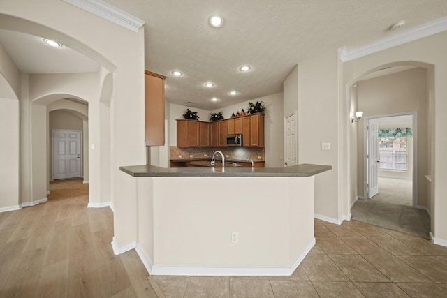 1910 Edenfield Ln, Sugar Land, TX 77479 - kitchen featuring stainless steel microwave, brown cabinets, dark countertops, arched walkways, and recessed lighting