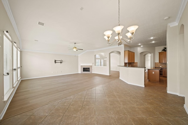 1910 Edenfield Ln, Sugar Land, TX 77479 - unfurnished living room with ceiling fan, ornamental molding, plenty of natural light, a tiled fireplace, and arched walkways