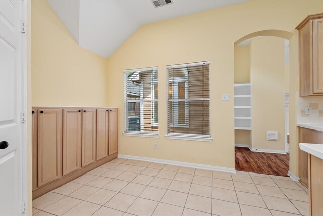 13014 Vivienne Westmoreland Dr, Cypress, TX 77429 - unfurnished dining area featuring vaulted ceiling, arched walkways, light tile patterned flooring, and baseboards
