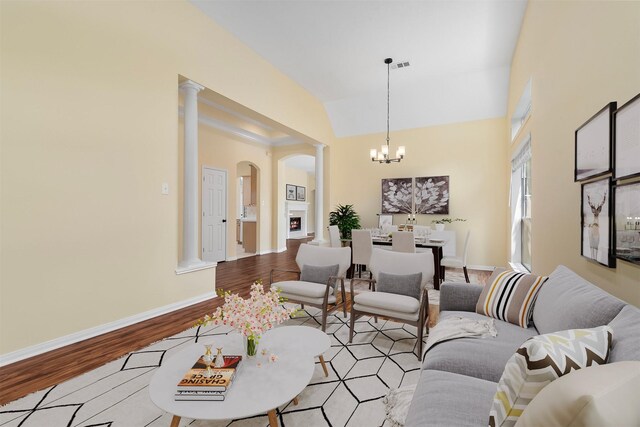13014 Vivienne Westmoreland Dr, Cypress, TX 77429 - living area featuring arched walkways, a chandelier, wood finished floors, vaulted ceiling, and ornate columns