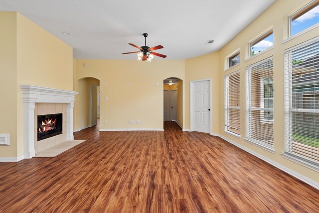 13014 Vivienne Westmoreland Dr, Cypress, TX 77429 - unfurnished living room featuring arched walkways, ceiling fan, wood finished floors, and a tiled fireplace
