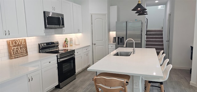 11378 Underwood St, Willis, TX 77318 - kitchen with stainless steel appliances, a sink, light wood-style flooring, tasteful backsplash, and a breakfast bar