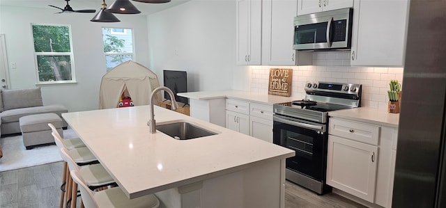 11378 Underwood St, Willis, TX 77318 - kitchen featuring stainless steel appliances, a sink, backsplash, wood finished floors, and white cabinetry
