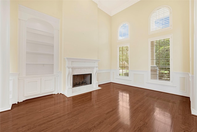 16506 Emilia Ct, Spring, TX 77379 - unfurnished living room with a wainscoted wall, wood finished floors, a high end fireplace, built in features, and a towering ceiling