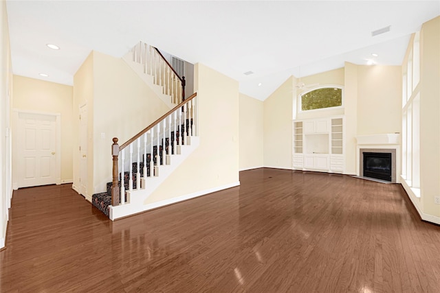 16506 Emilia Ct, Spring, TX 77379 - unfurnished living room featuring wood finished floors, high vaulted ceiling, stairs, a fireplace with flush hearth, and recessed lighting