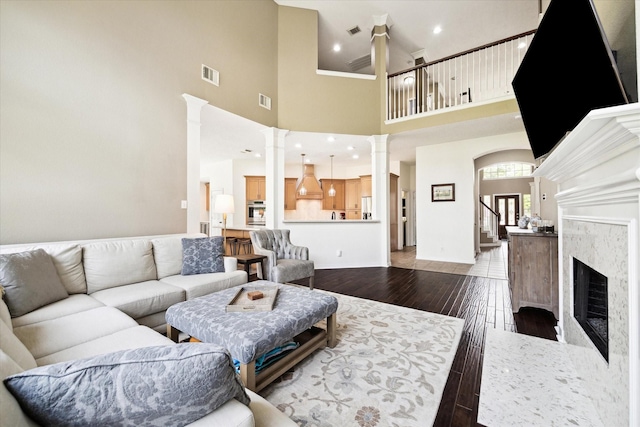 7327 Crescent Bridge Ct, Humble, TX 77396 - living room with decorative columns, dark wood finished floors, a high ceiling, stairway, and a high end fireplace
