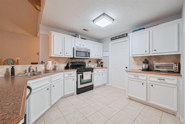 109 Moonspinner, Conroe, TX 77356 - kitchen featuring stainless steel appliances, a sink, decorative backsplash, white cabinets, and light tile patterned flooring