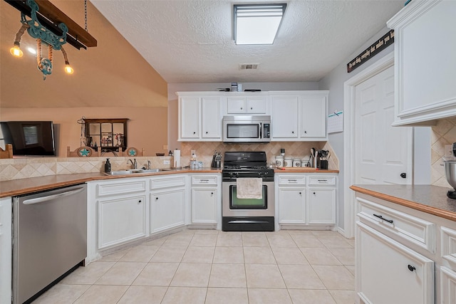 109 Moonspinner, Conroe, TX 77356 - kitchen with appliances with stainless steel finishes, a sink, tasteful backsplash, a textured ceiling, and white cabinetry