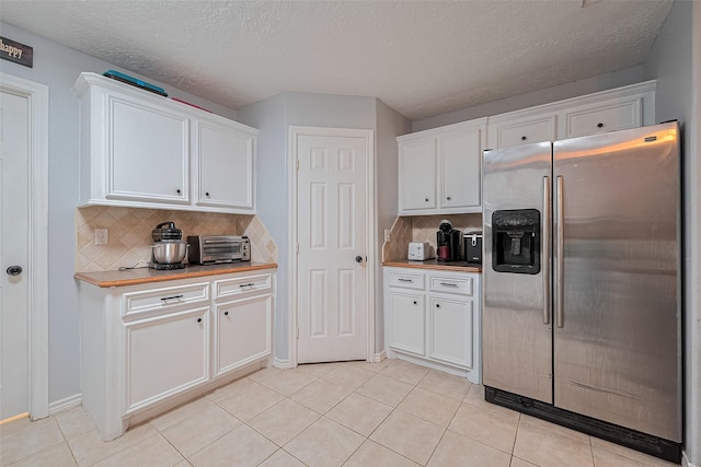 109 Moonspinner, Conroe, TX 77356 - kitchen with stainless steel fridge, white cabinets, decorative backsplash, light tile patterned flooring, and a textured ceiling