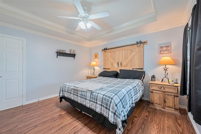109 Moonspinner, Conroe, TX 77356 - bedroom featuring wood finished floors, a tray ceiling, crown molding, a barn door, and baseboards