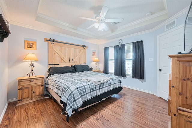 109 Moonspinner, Conroe, TX 77356 - bedroom featuring a tray ceiling, wood finished floors, baseboards, a barn door, and ornamental molding