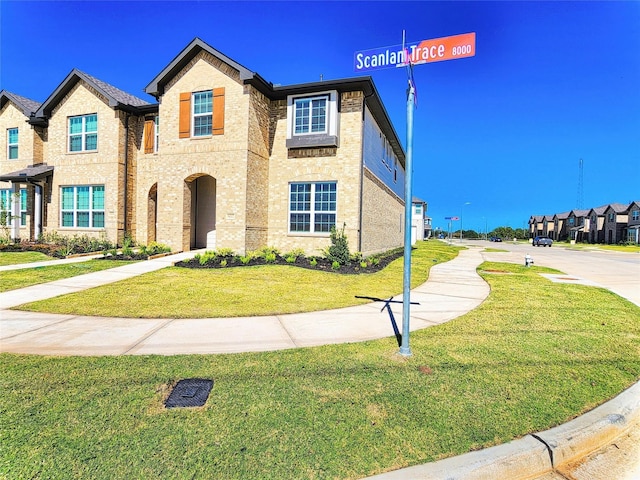 townhome / multi-family property with a front lawn and brick siding