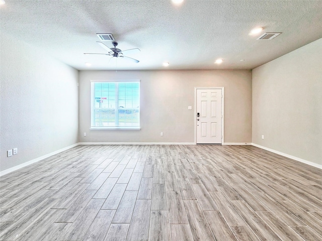 unfurnished living room with light wood-style flooring, a ceiling fan, a textured ceiling, and baseboards
