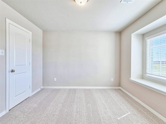 spare room featuring carpet floors, baseboards, and a textured ceiling