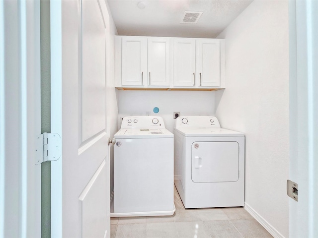 clothes washing area with cabinet space, separate washer and dryer, light tile patterned floors, and baseboards