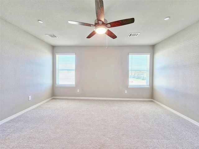 empty room featuring light colored carpet, ceiling fan, baseboards, and a textured wall