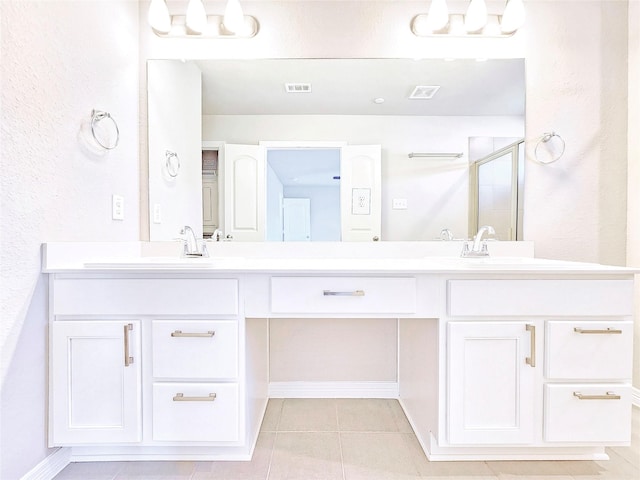 full bathroom with tile patterned floors, a stall shower, double vanity, baseboards, and a textured wall
