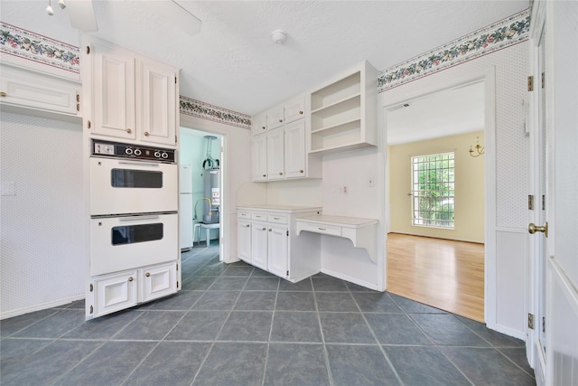 4822 Droddy St, Houston, TX 77091 - kitchen with double oven, white cabinetry, dark tile patterned flooring, open shelves, and baseboards