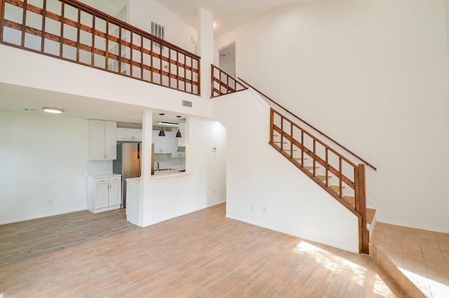 3538 Ocee St, Houston, TX 77063 - unfurnished living room with stairway, a towering ceiling, light wood finished floors, and baseboards