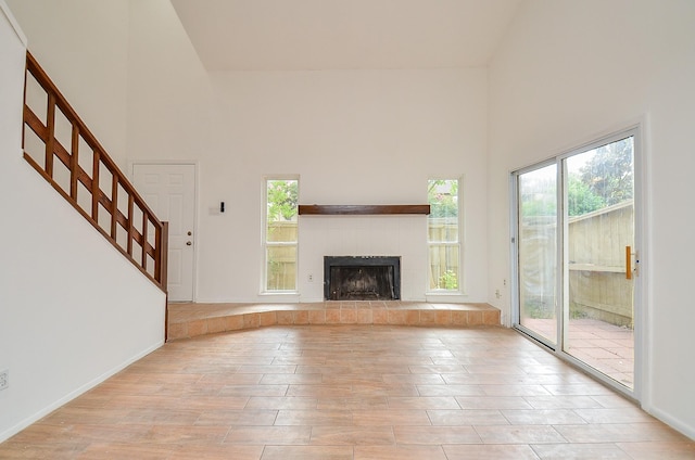 3538 Ocee St, Houston, TX 77063 - unfurnished living room featuring a towering ceiling, light wood-style flooring, stairs, and a fireplace