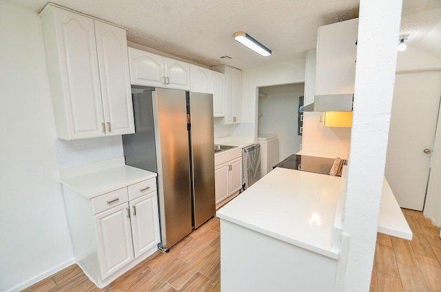 3538 Ocee St, Houston, TX 77063 - kitchen with washer and clothes dryer, appliances with stainless steel finishes, light wood-type flooring, and white cabinets