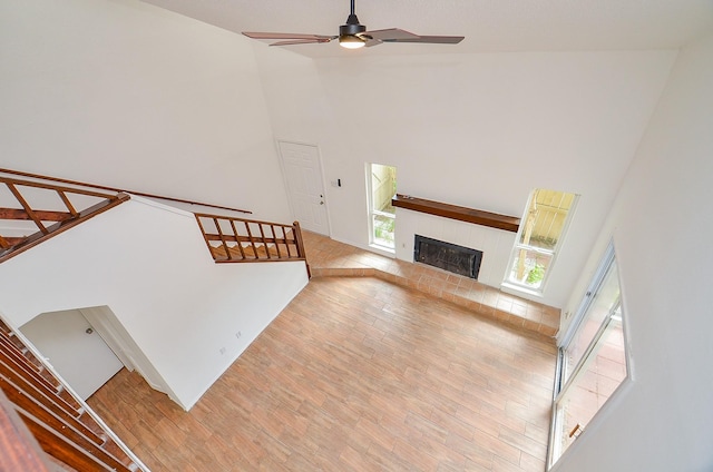 3538 Ocee St, Houston, TX 77063 - unfurnished living room with light wood-style floors, high vaulted ceiling, a ceiling fan, a fireplace with raised hearth, and stairs