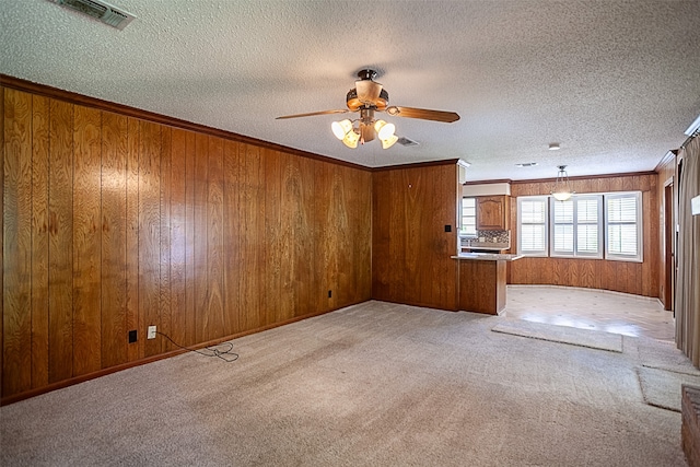 2812 Fairway Dr, Orange, TX 77630 - unfurnished living room featuring light colored carpet, a ceiling fan, a textured ceiling, wood walls, and crown molding