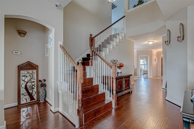 3619 Canton Hills Ln, Missouri City, TX 77459 - staircase featuring a towering ceiling, hardwood / wood-style floors, arched walkways, and baseboards