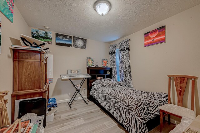 3619 Canton Hills Ln, Missouri City, TX 77459 - bedroom featuring light wood-type flooring, a textured ceiling, and baseboards