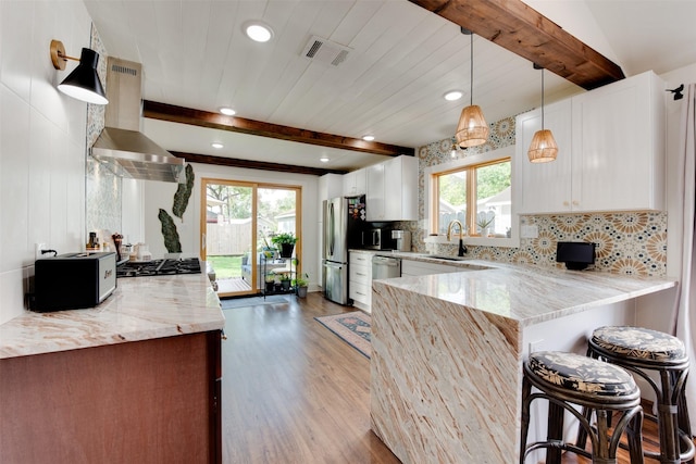 1127 Nadine St, Houston, TX 77009 - kitchen with a sink, wall chimney range hood, wood finished floors, beamed ceiling, and appliances with stainless steel finishes