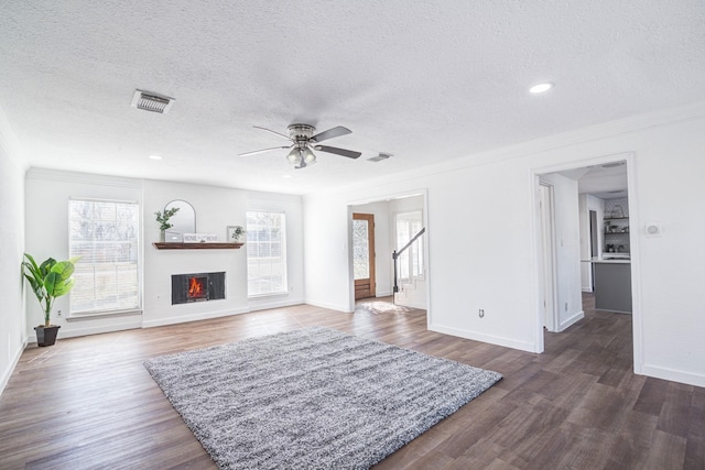 102 Banyan St, Lake Jackson, TX 77566 - unfurnished living room featuring plenty of natural light, a textured ceiling, a ceiling fan, ornamental molding, and a warm lit fireplace