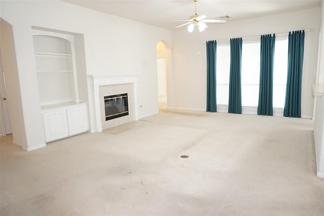11714 Goldstream Ct, Tomball, TX 77377 - unfurnished living room with arched walkways, light carpet, a ceiling fan, and a fireplace
