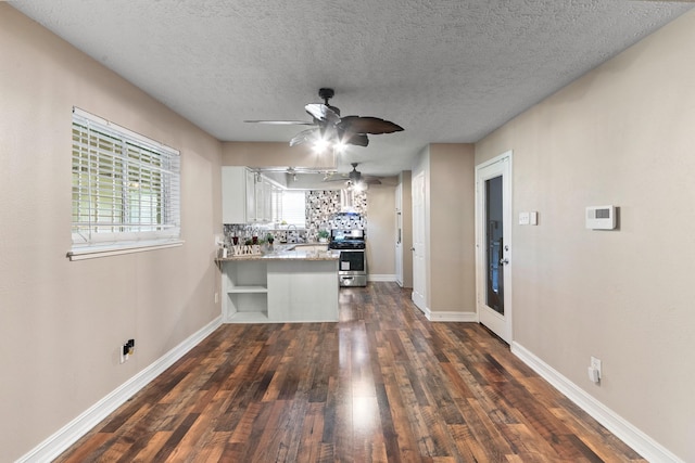 4302 Marchant Rd, Houston, TX 77047 - kitchen featuring a peninsula, dark wood-style flooring, ceiling fan, stainless steel range, and white cabinets