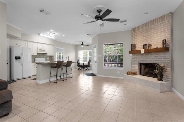 living room featuring light tile patterned flooring, baseboards, ceiling fan, crown molding, and recessed lighting
