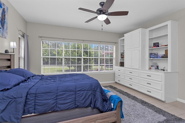 bedroom featuring baseboards, light tile patterned flooring, and a ceiling fan