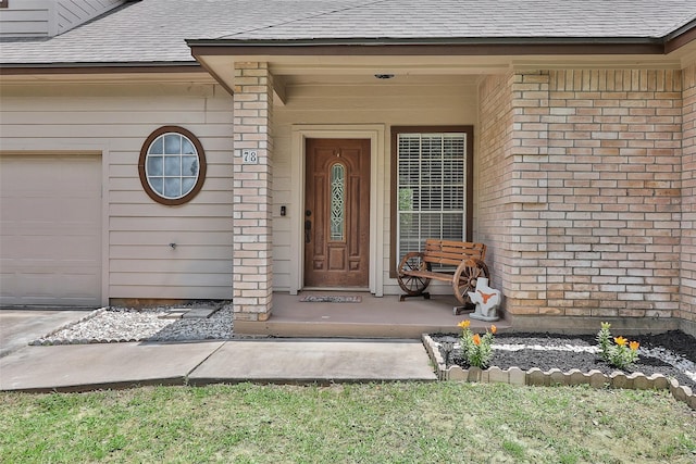 property entrance with a shingled roof, brick siding, covered porch, and an attached garage