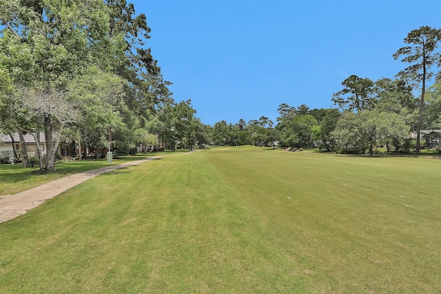 view of property's community with view of wooded area, a yard, and view of golf course