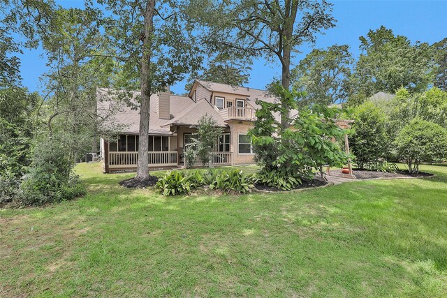 rear view of property featuring a sunroom, a lawn, and a chimney