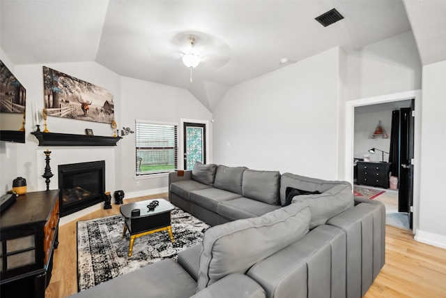 19266 Hazel Firs Ct, Magnolia, TX 77355 - living room featuring vaulted ceiling, light wood-style floors, a glass covered fireplace, and baseboards