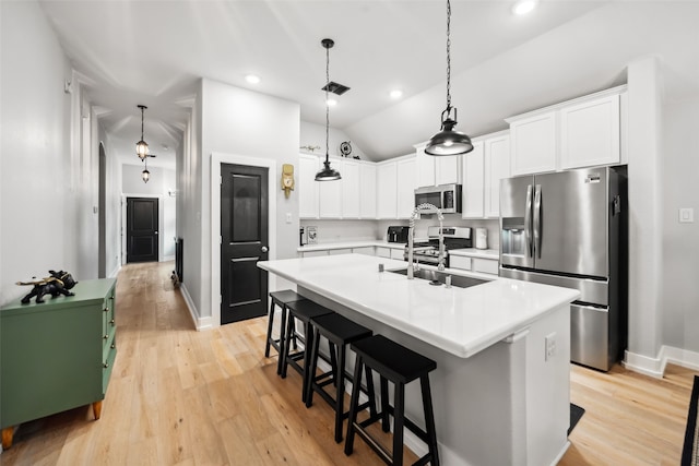 19266 Hazel Firs Ct, Magnolia, TX 77355 - kitchen featuring appliances with stainless steel finishes, a sink, vaulted ceiling, an island with sink, and light wood finished floors