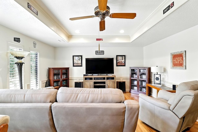 17714 Treeloch Ln, Spring, TX 77379 - living room with light wood-style floors, a ceiling fan, a tray ceiling, wainscoting, and recessed lighting