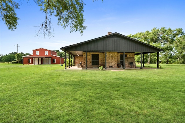 3428 S Main St, Anahuac, TX 77514 - rear view of house with a yard, brick siding, a chimney, and a patio