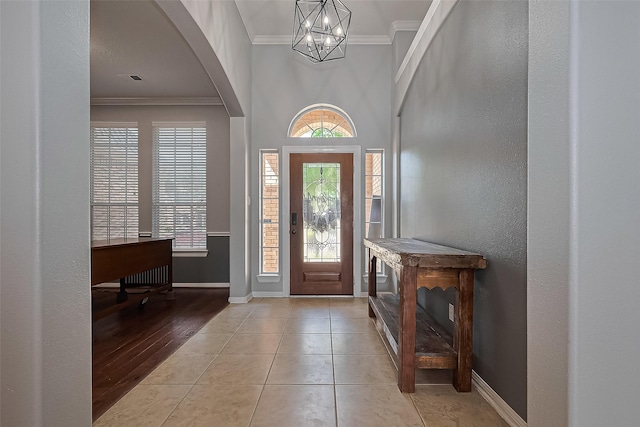 13903 Autumn Grove Ct, Rosharon, TX 77583 - entrance foyer featuring crown molding, arched walkways, baseboards, a chandelier, and tile patterned flooring