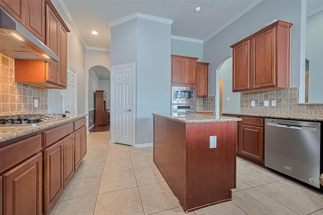 13903 Autumn Grove Ct, Rosharon, TX 77583 - kitchen with appliances with stainless steel finishes, arched walkways, under cabinet range hood, a center island, and backsplash