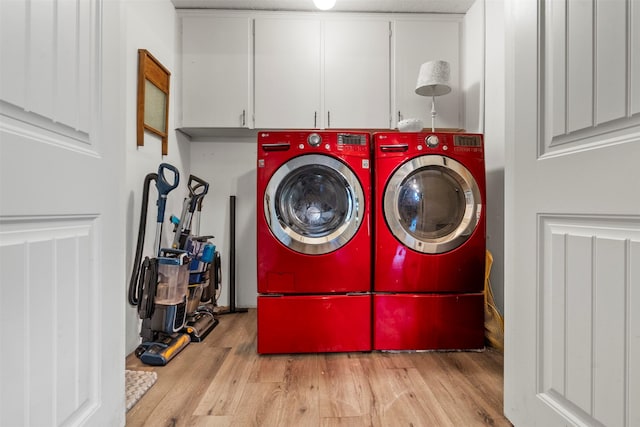 laundry room with washer and clothes dryer, cabinet space, and wood finished floors