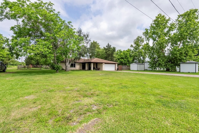 view of grassy yard with a storage unit, an attached garage, and an outdoor structure