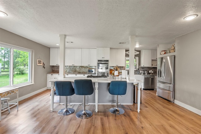kitchen featuring stainless steel appliances, backsplash, a kitchen breakfast bar, baseboards, and a textured ceiling