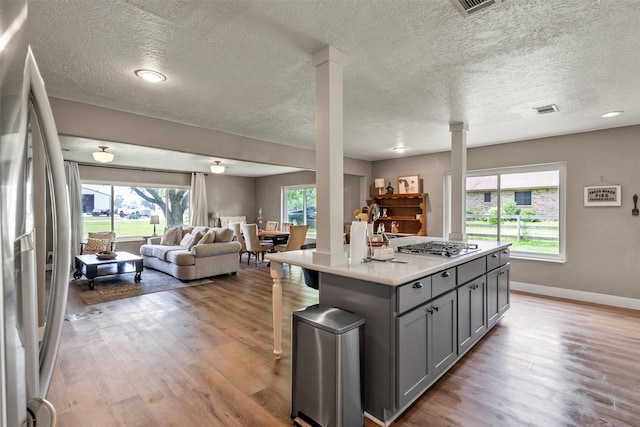 kitchen with gray cabinetry, stainless steel appliances, open floor plan, light wood-style floors, and light countertops